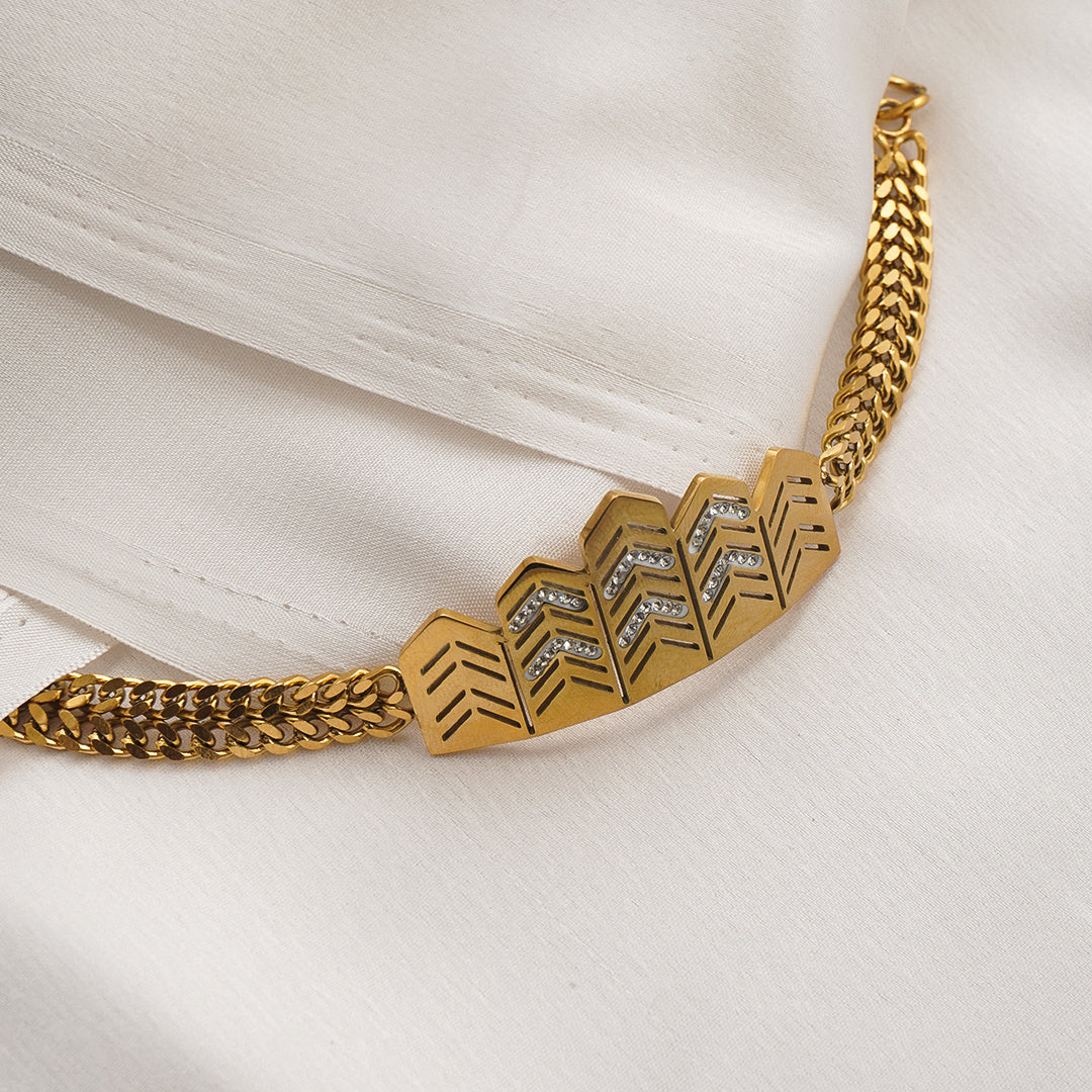 Gold bracelet with geometric design on a white fabric background