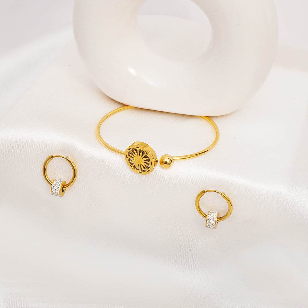 Gold bracelet and earrings on a white surface