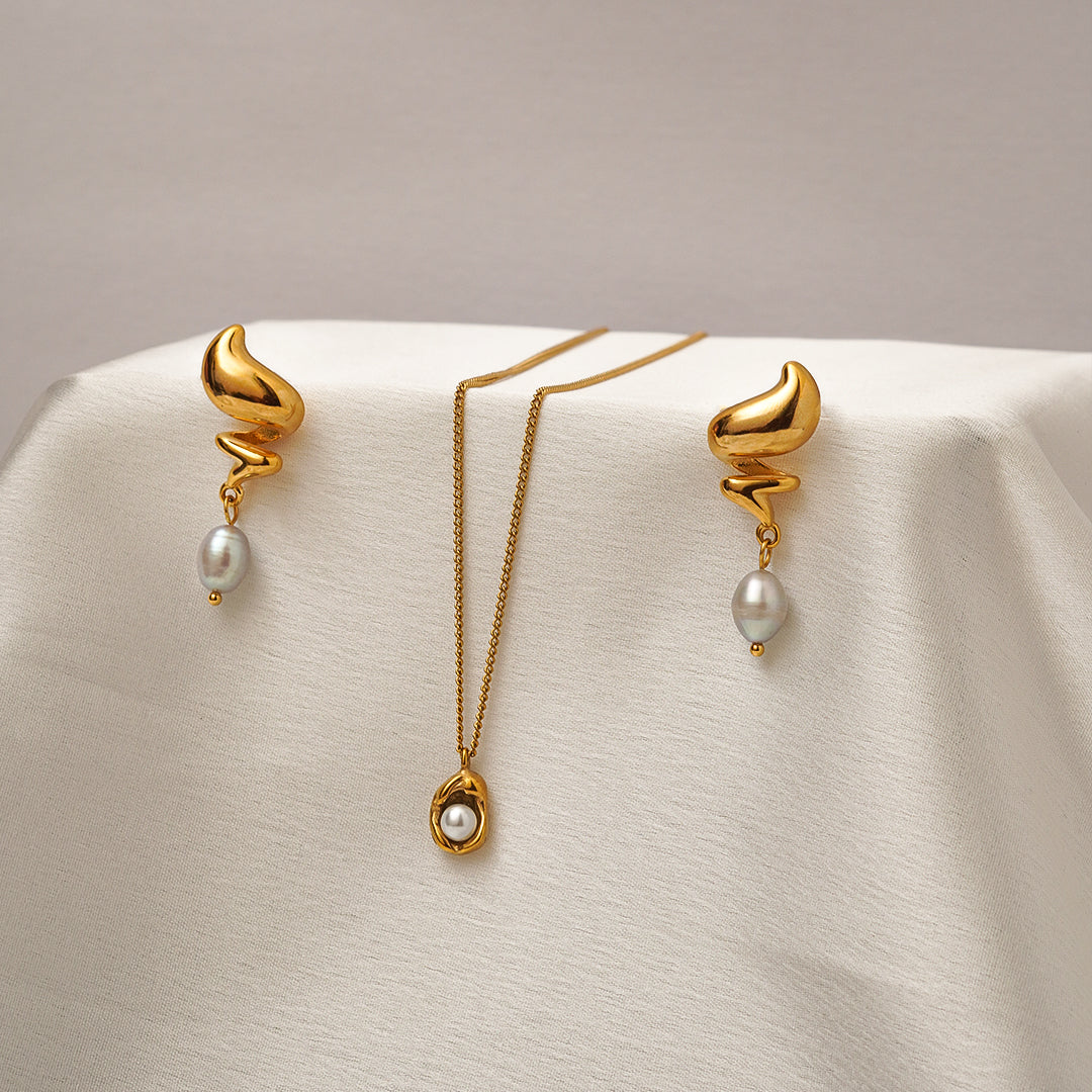 Gold earrings with pearl drops on a beige background