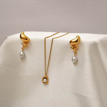Gold earrings with pearl drops on a beige background