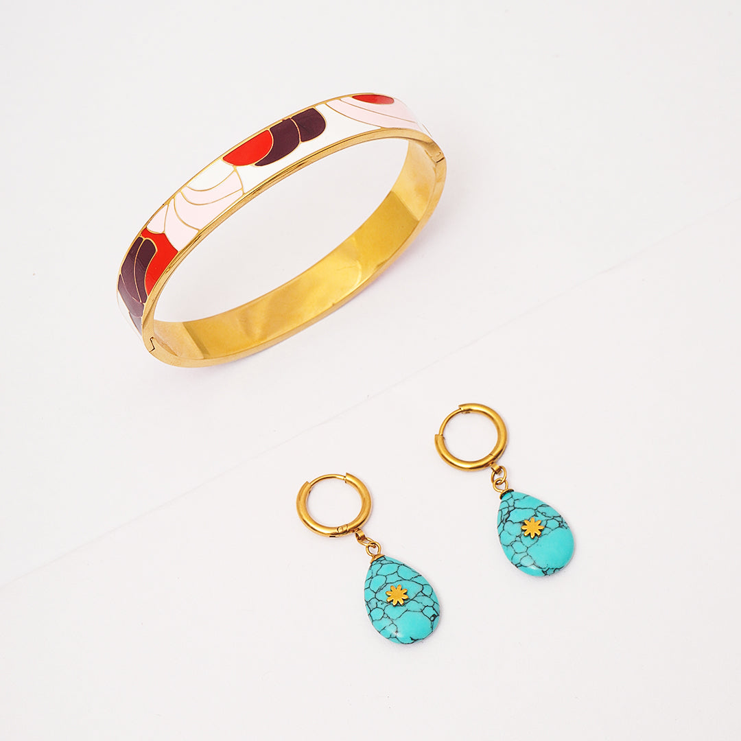 Jewelry set with a gold bangle and turquoise earrings on a white background
