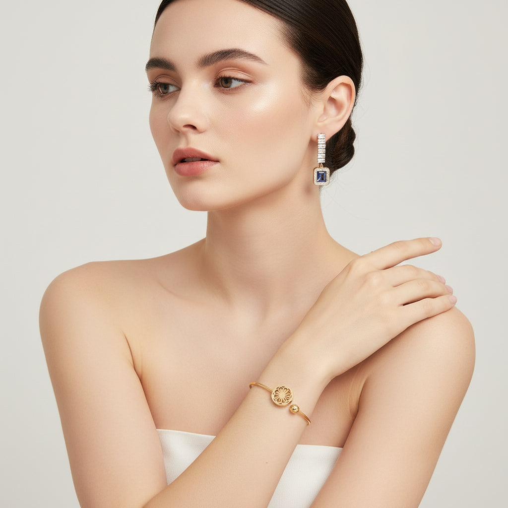 Gold bracelet and earrings with blue gemstones on a white background