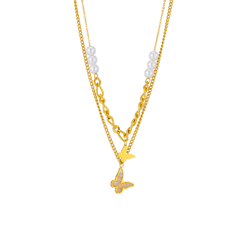 Gold necklace with butterfly pendant and pearl beads on a white background