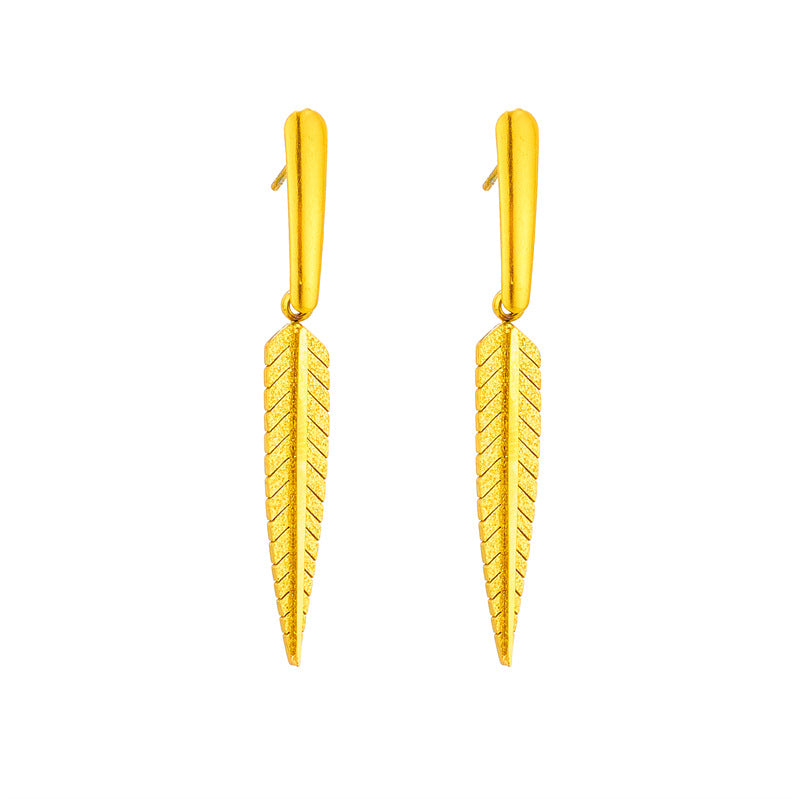 Pair of gold earrings with a leaf-like design on a white background