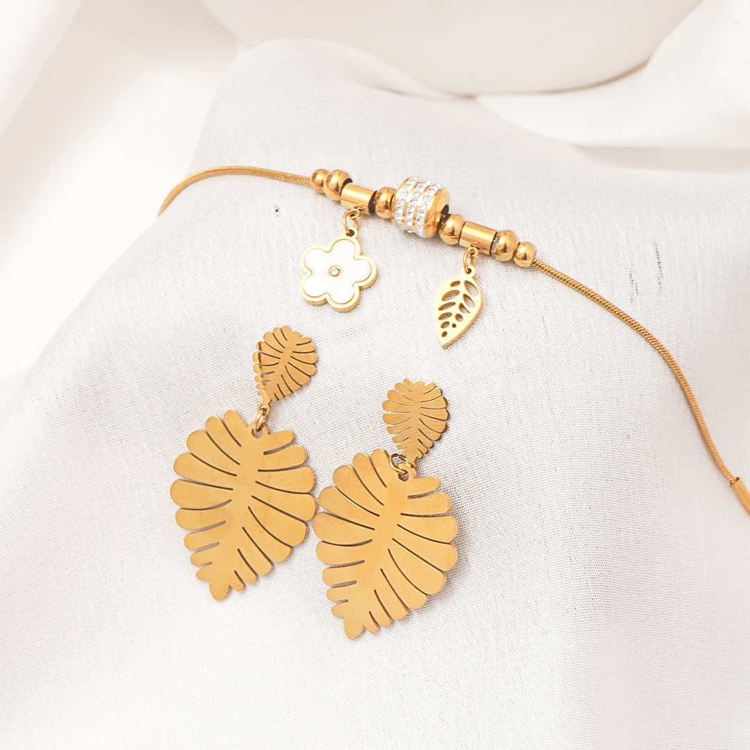 Gold leaf earrings with a matching necklace on a white fabric background