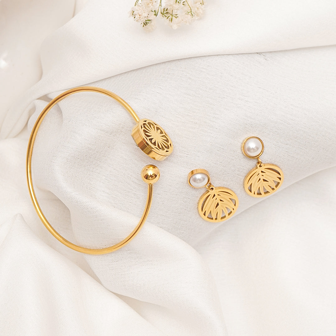 Gold bracelet and earrings on a white fabric background