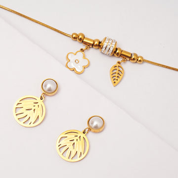 Gold bracelet with charms and earrings on a light gray background
