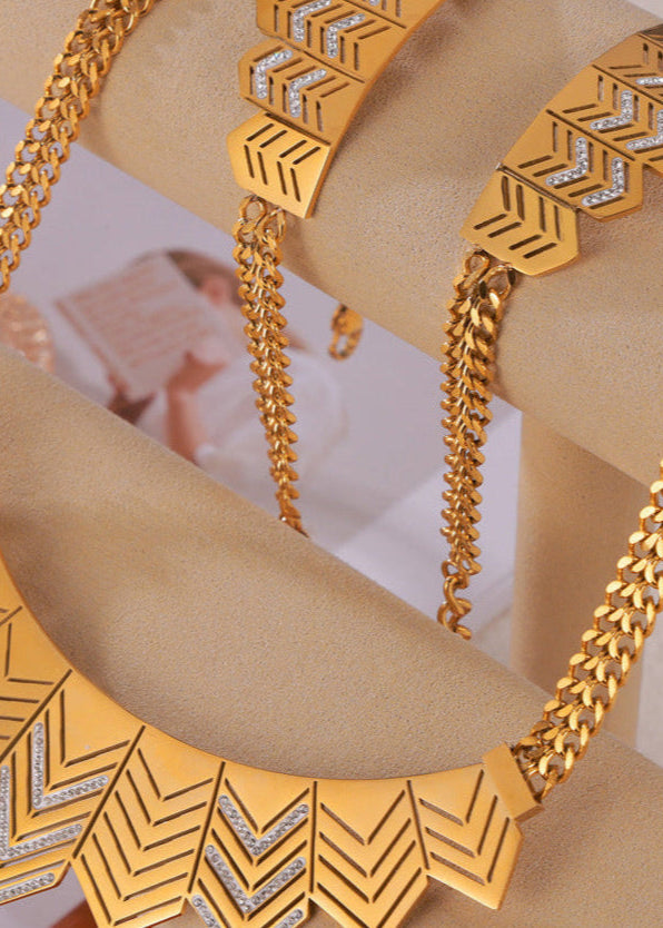 Gold necklace with geometric design on a beige stand