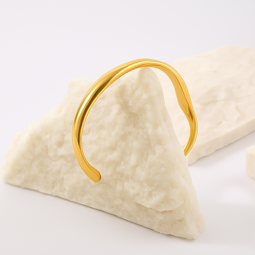 Gold bracelet on a triangular piece of fabric with a white background