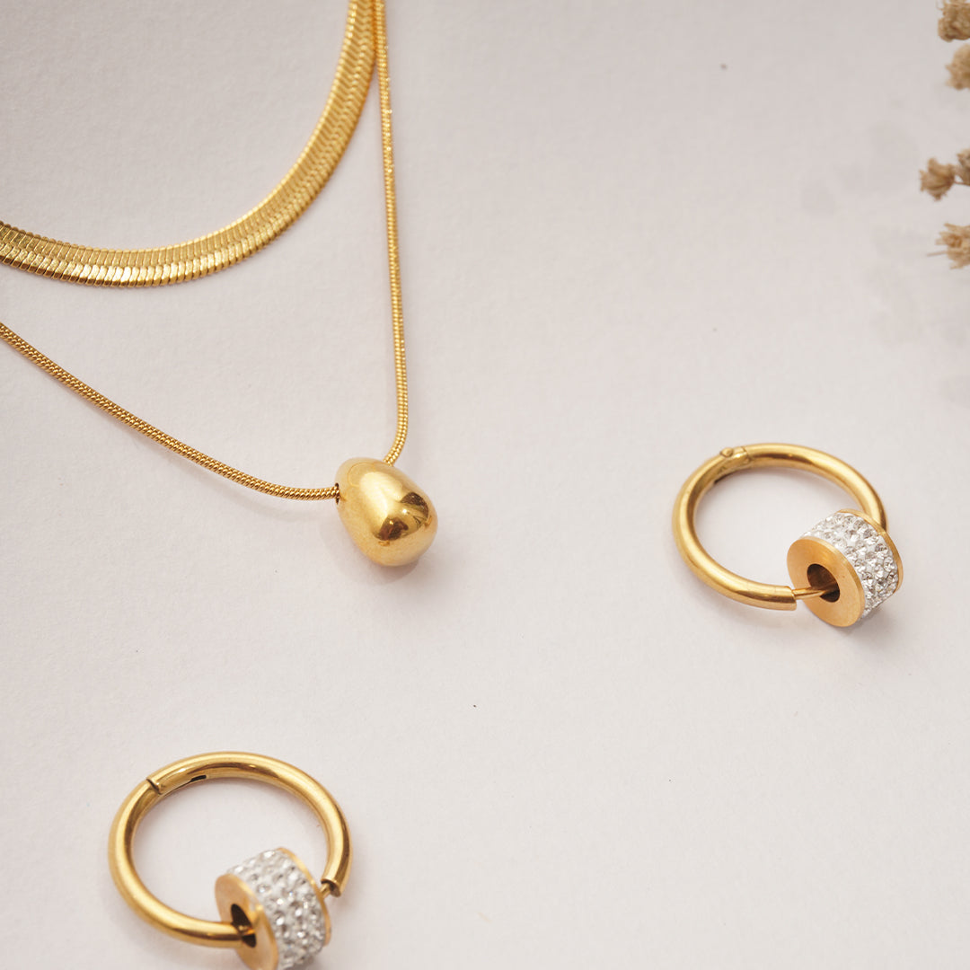Gold necklace and hoop earrings on a light background