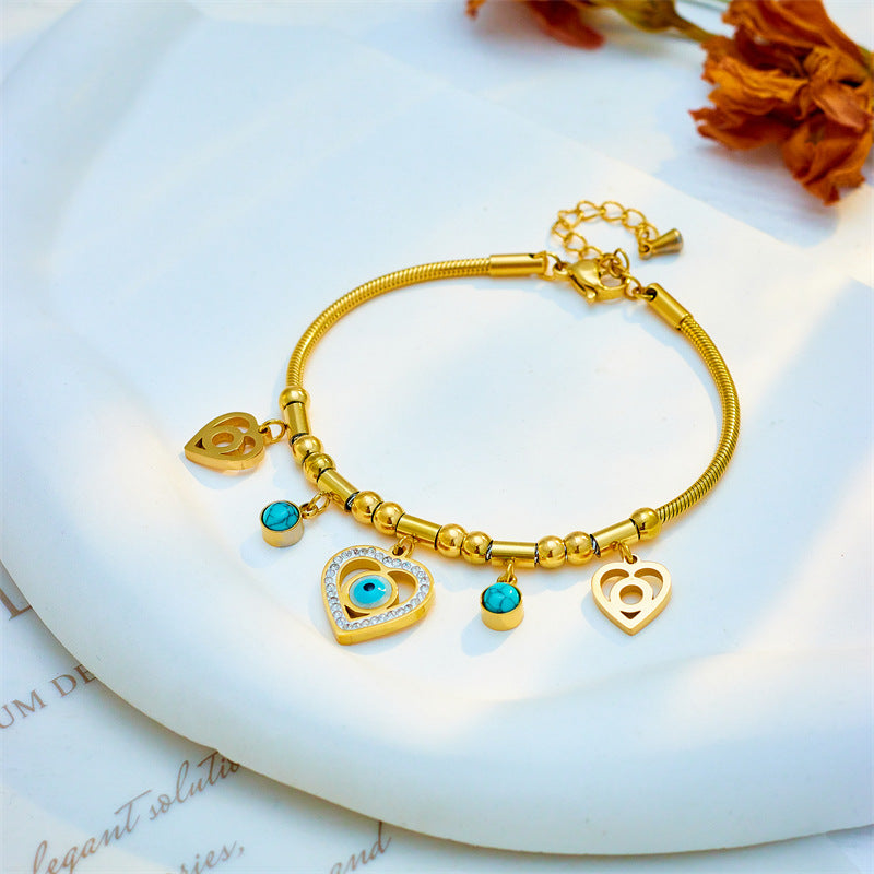 Gold bracelet with heart-shaped charms on a white surface with flowers