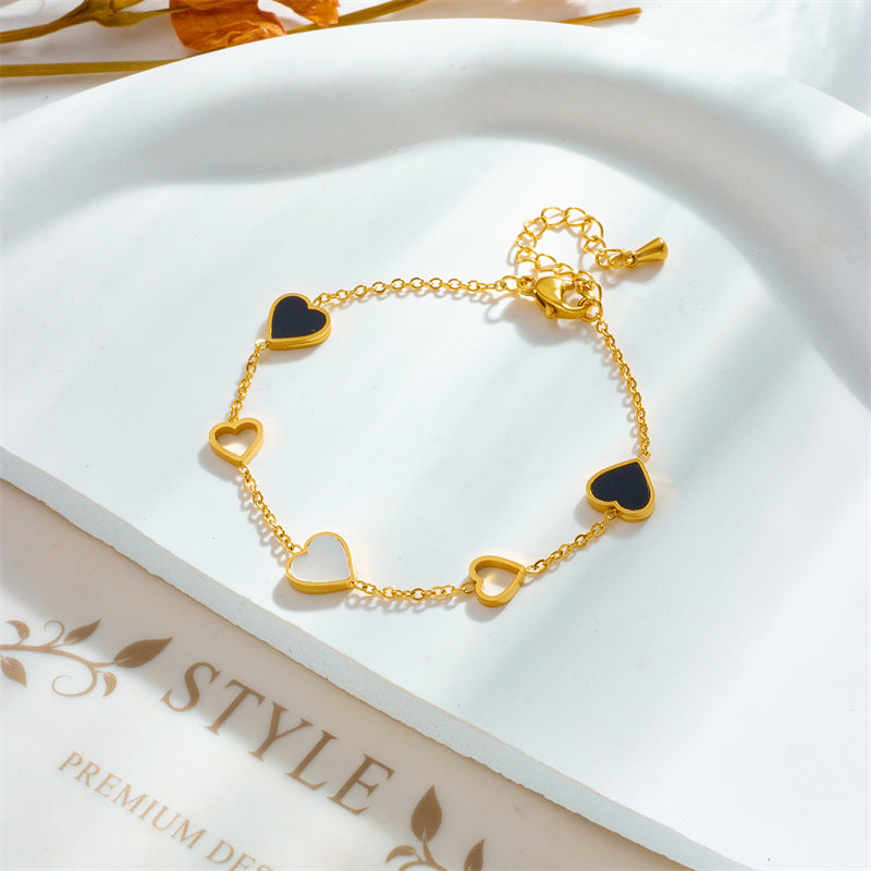 Gold bracelet with heart-shaped charms on a white surface