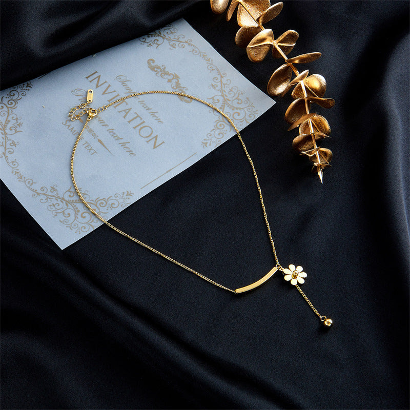 Gold necklace and earrings with a floral pendant on a light background