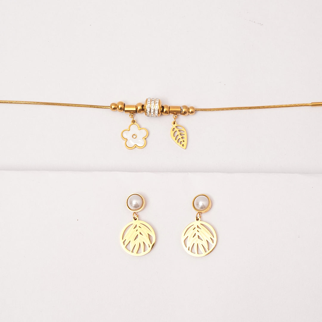 Gold necklace with floral and leaf charms and matching earrings on a white background