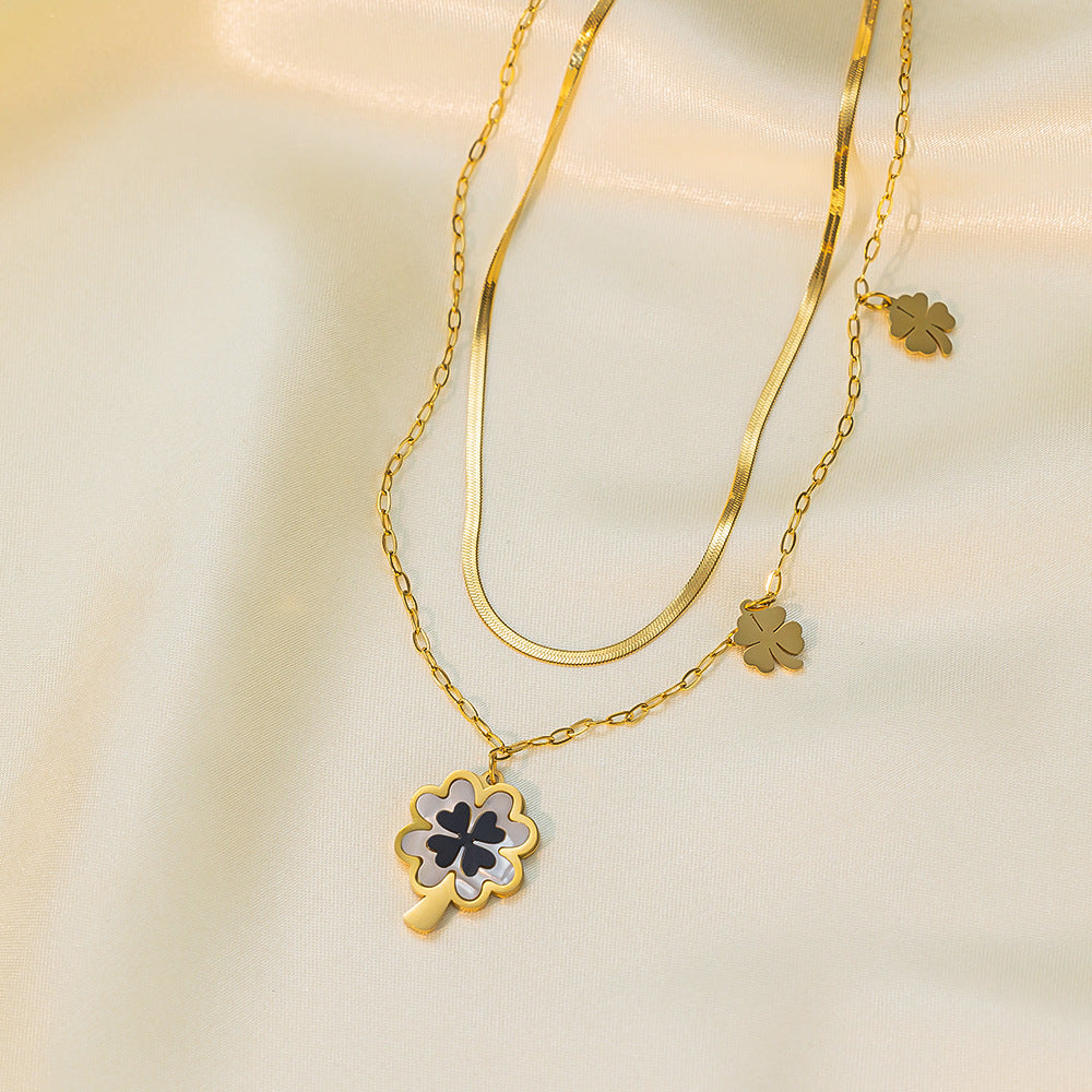Gold necklace and earrings with clover designs on a beige background