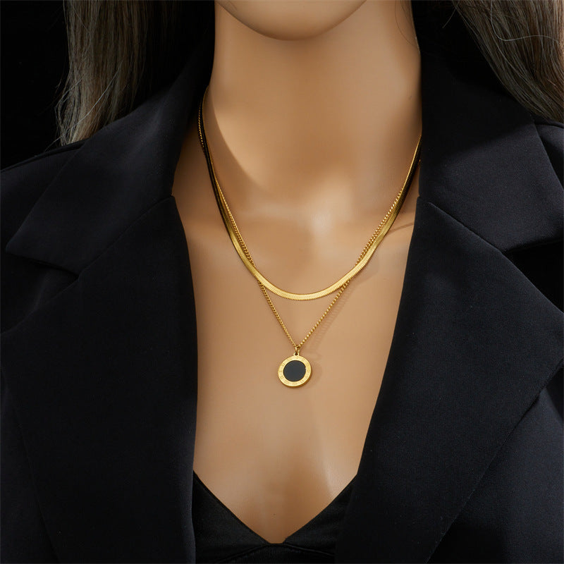 Gold necklace with a black pendant on a white surface