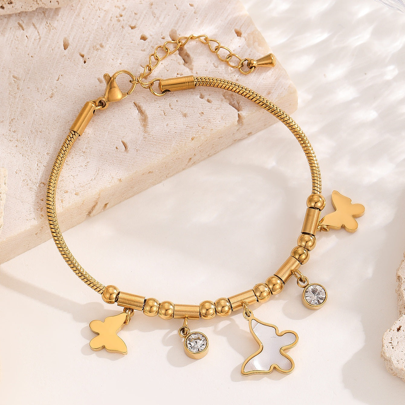 Gold bracelet with star-shaped charms on a light stone background