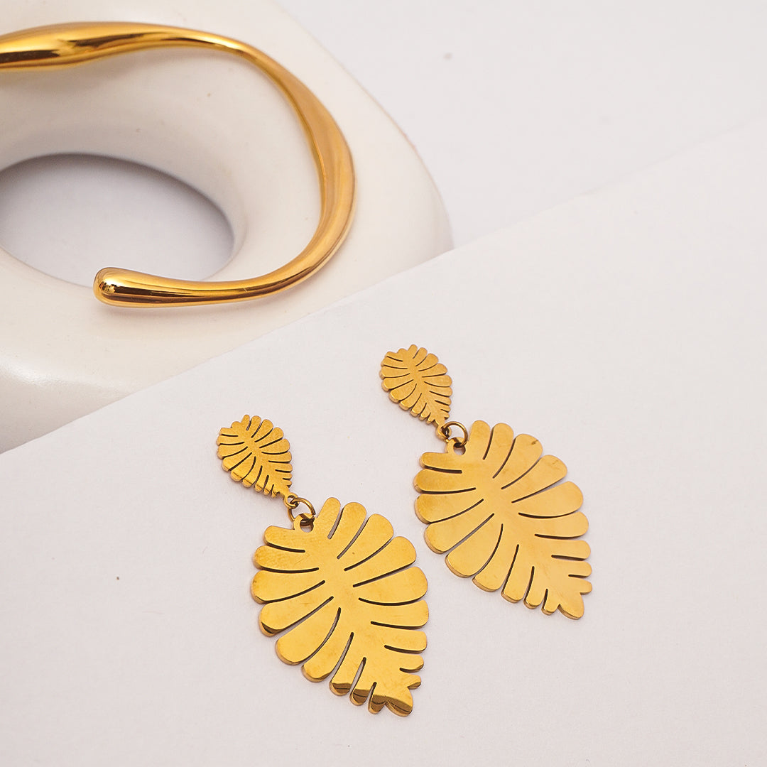 Gold leaf-shaped earrings on a white background