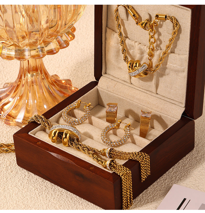 Gold jewelry set including bracelets, earrings, and rings displayed in an open wooden jewelry box.