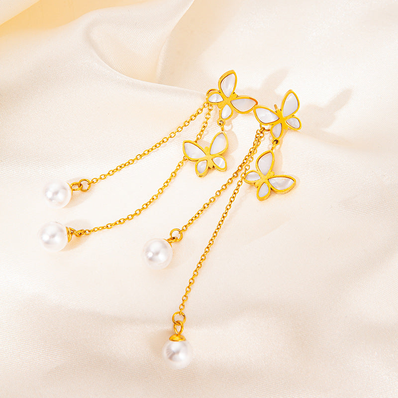 Gold necklace with butterfly pendants and pearls on a beige background