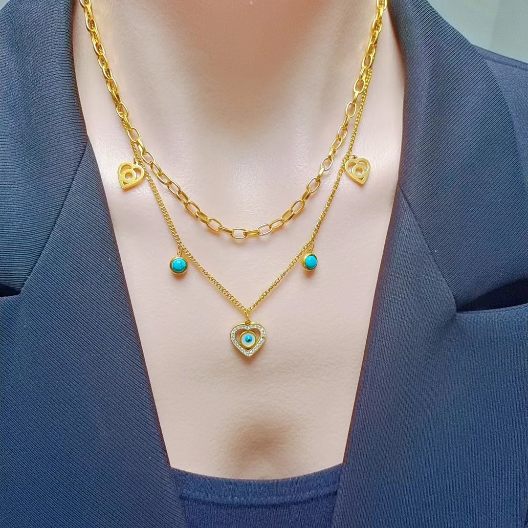 Gold necklaces with heart and turquoise stone pendants on a person wearing a blue blazer.