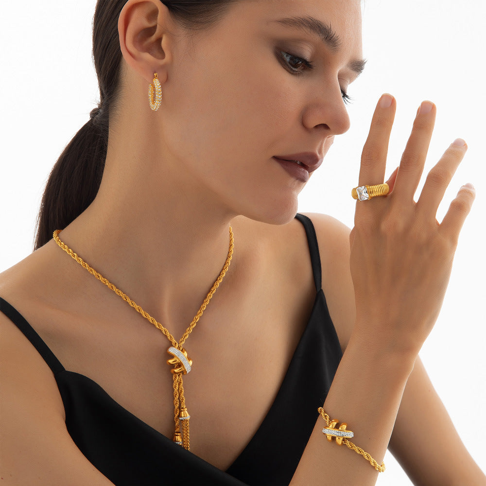 Woman wearing gold jewelry including a necklace, earrings, and ring on a white background