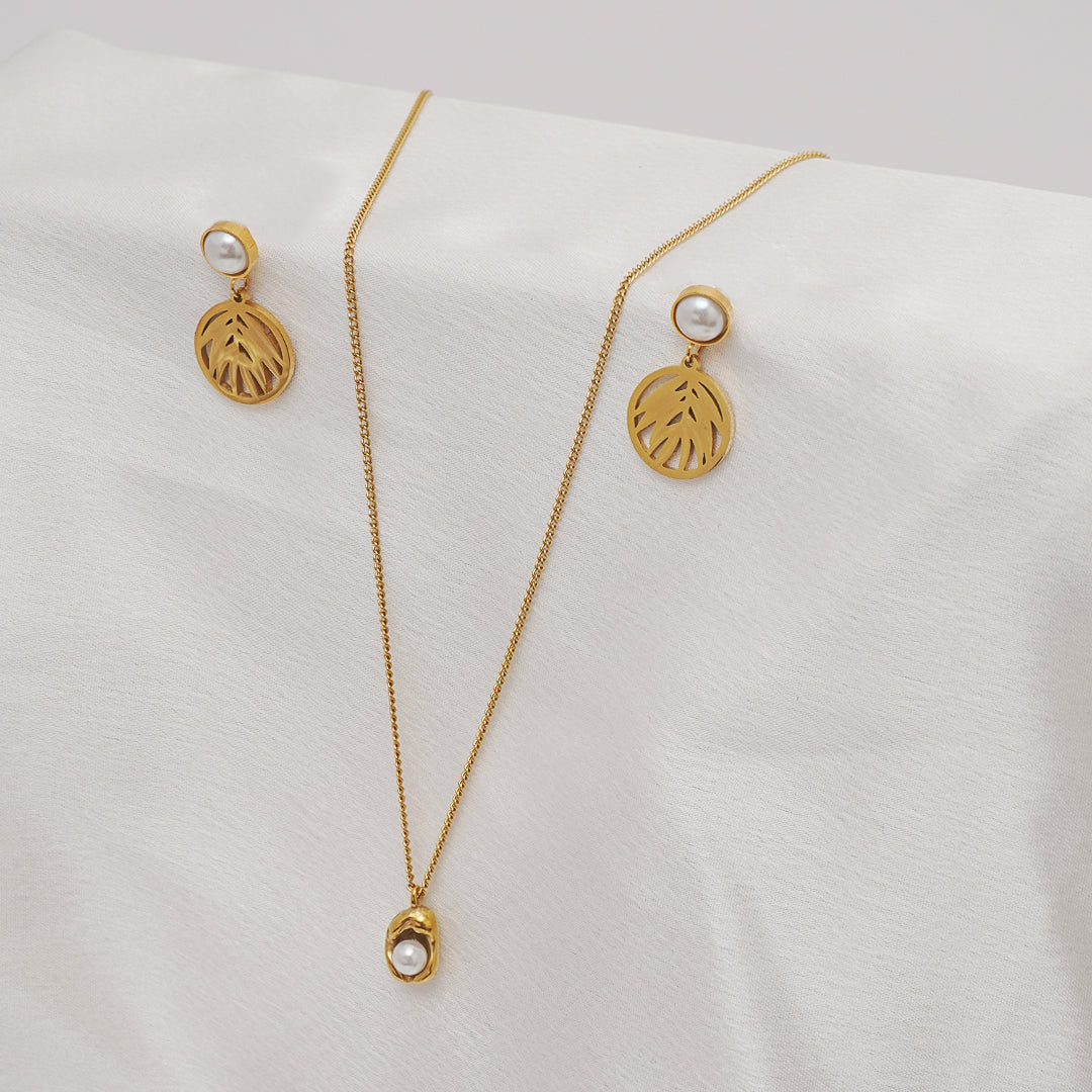 Gold necklace and earrings on a white cushion