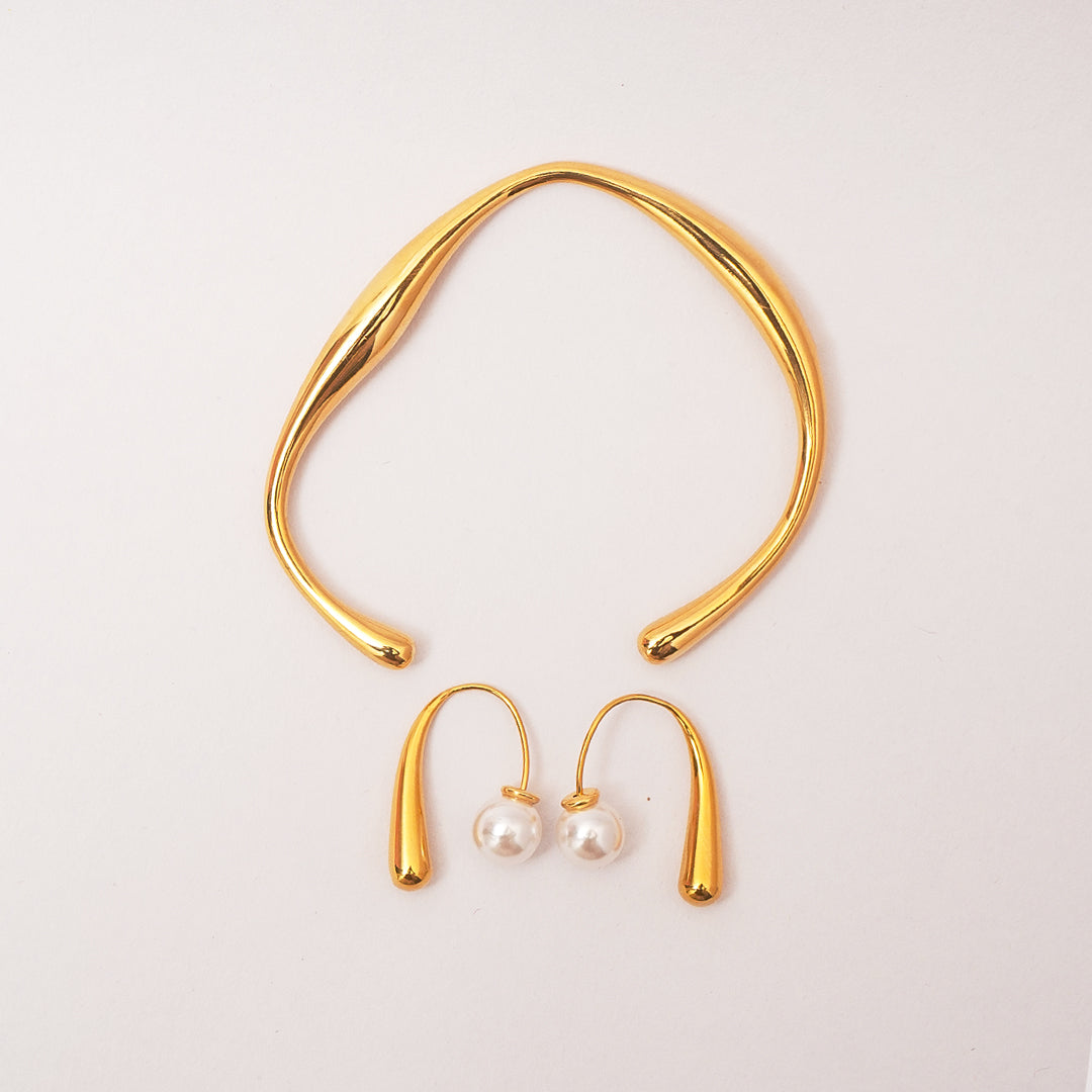 Gold necklace and earrings on a light gray background