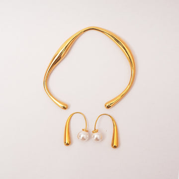 Gold necklace and earrings on a light gray background