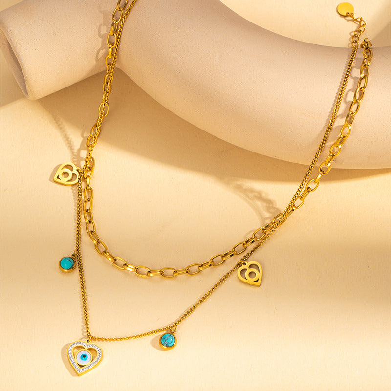 Gold necklaces with heart and turquoise charm on a beige background