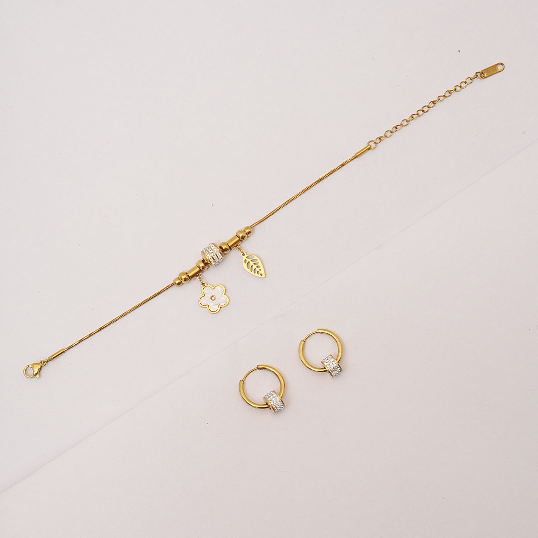 Gold jewelry set including a bracelet and two rings on a light gray background