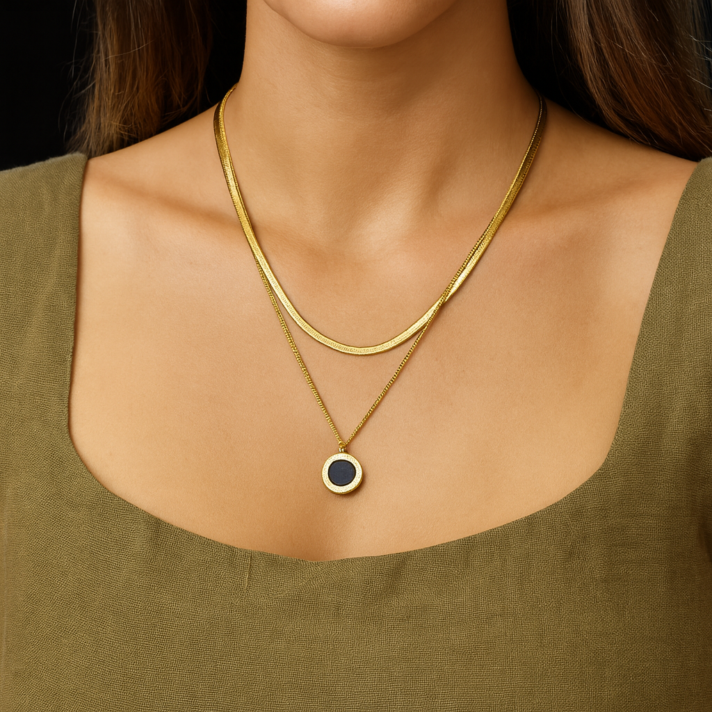 Gold necklace with a pendant and matching earrings on a white surface
