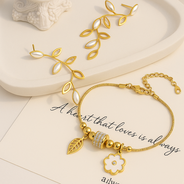 Gold bracelet with leaf designs on a white surface with a quote card.