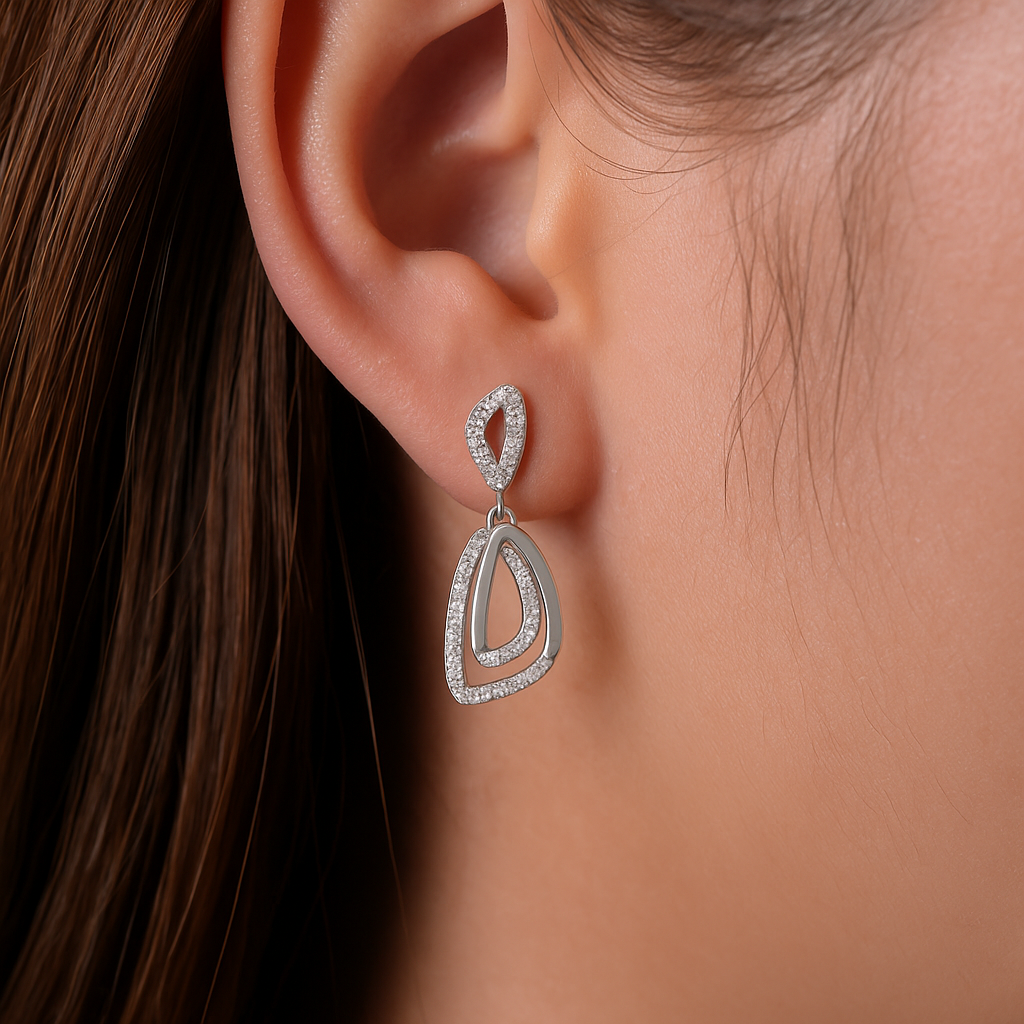 Silver teardrop earring worn by a person with brown hair.