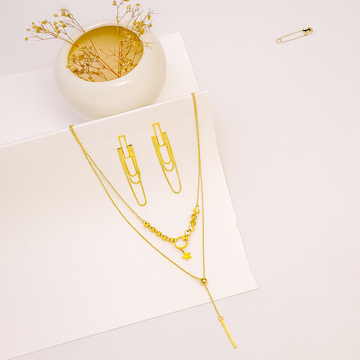Gold necklaces on a white surface with a small decorative bowl and safety pin.