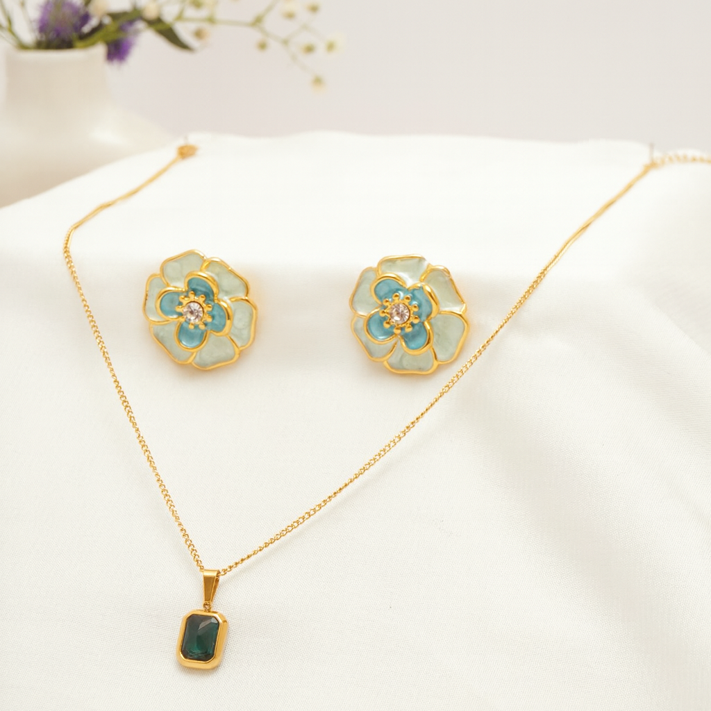 Gold necklace and earrings with floral designs on a white surface