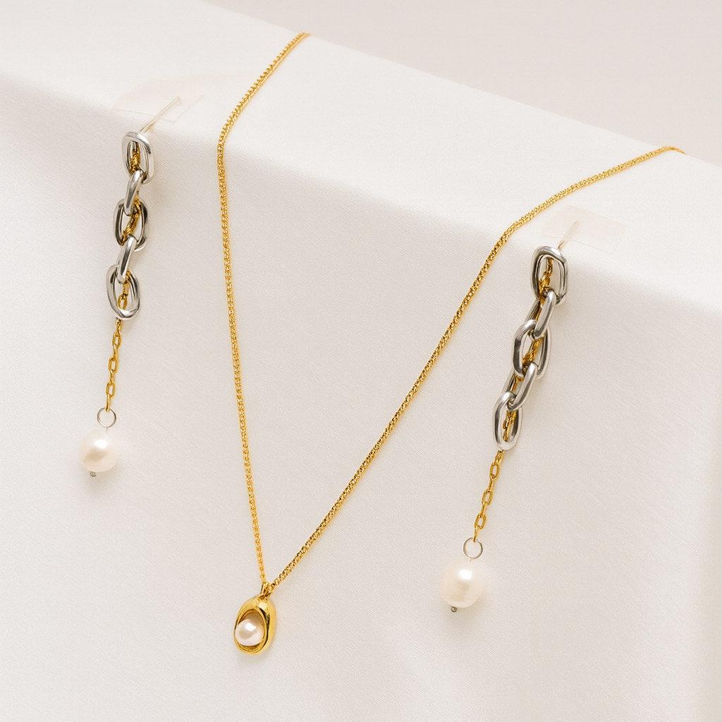 Two gold necklaces with pearl pendants on a white surface