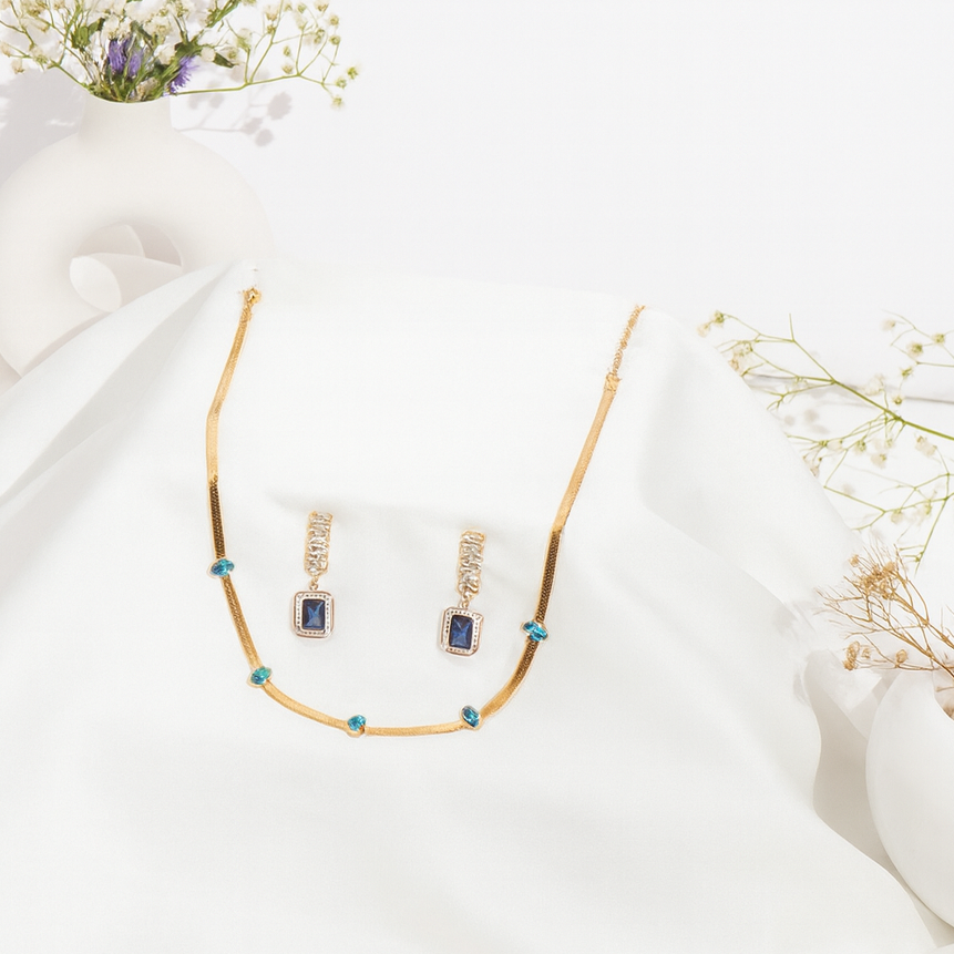 Gold necklace and earrings with gemstones on a white fabric background