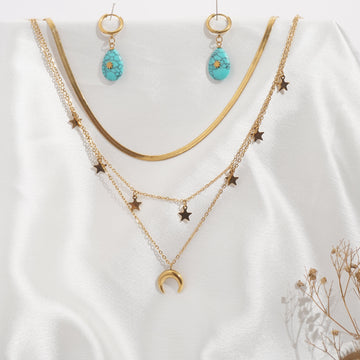 Gold necklace and earrings with blue stones on a white fabric background