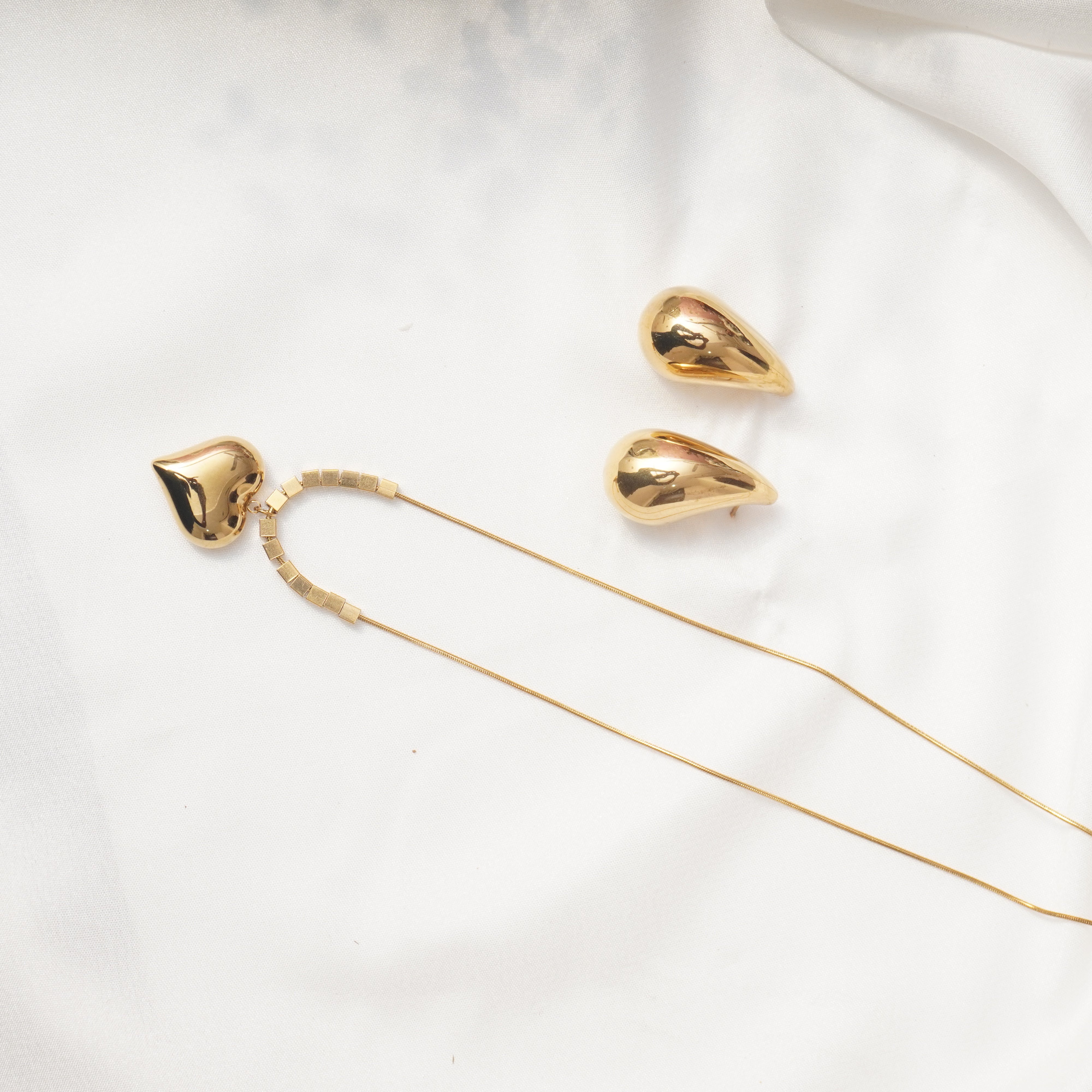 Gold necklace and earrings on a white fabric background