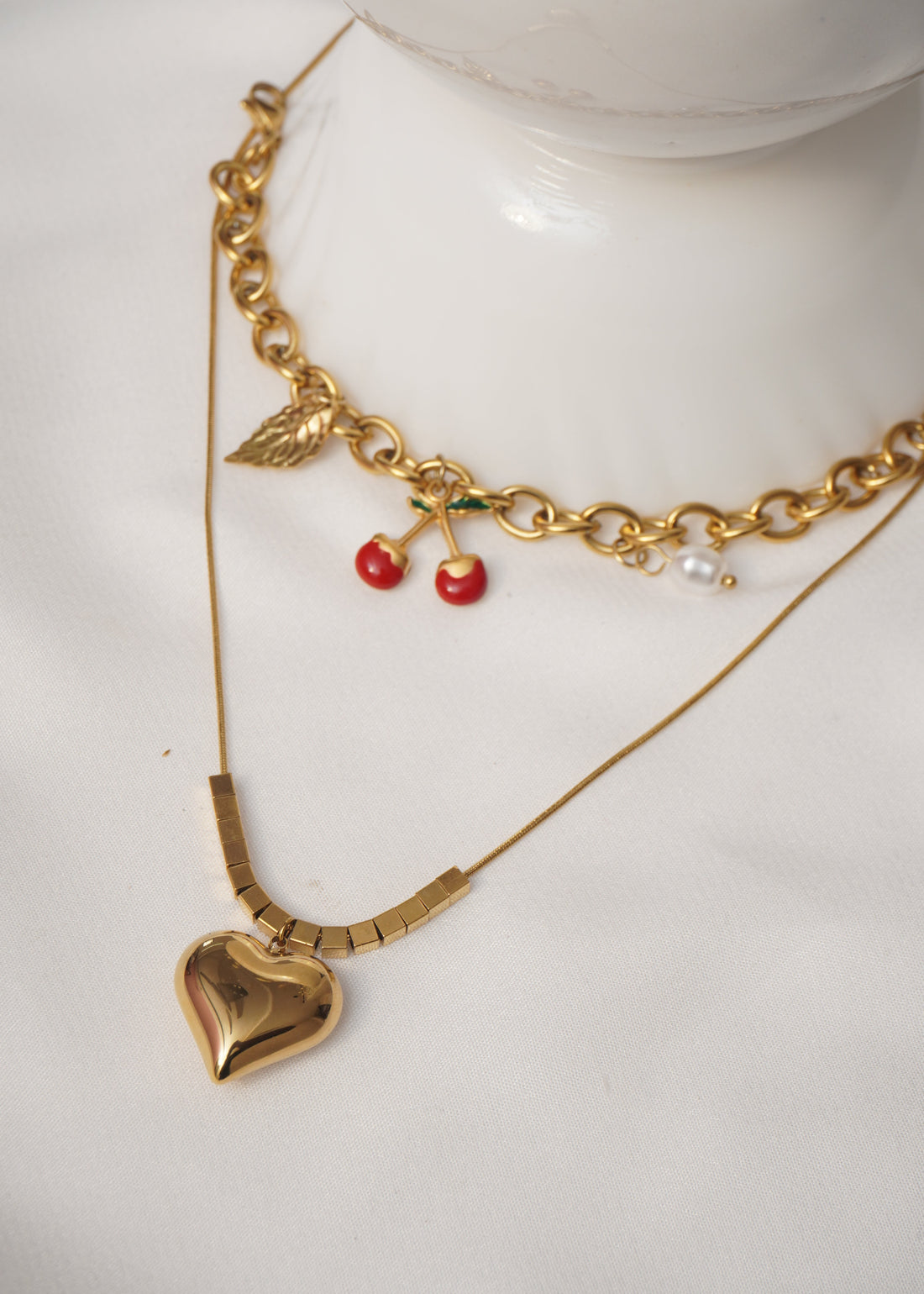 Gold bracelet with red berries and pearls on a white surface