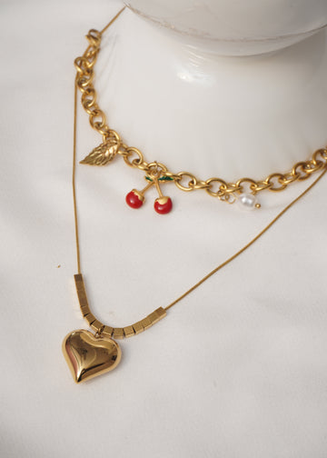 Gold bracelet with red berries and pearls on a white surface