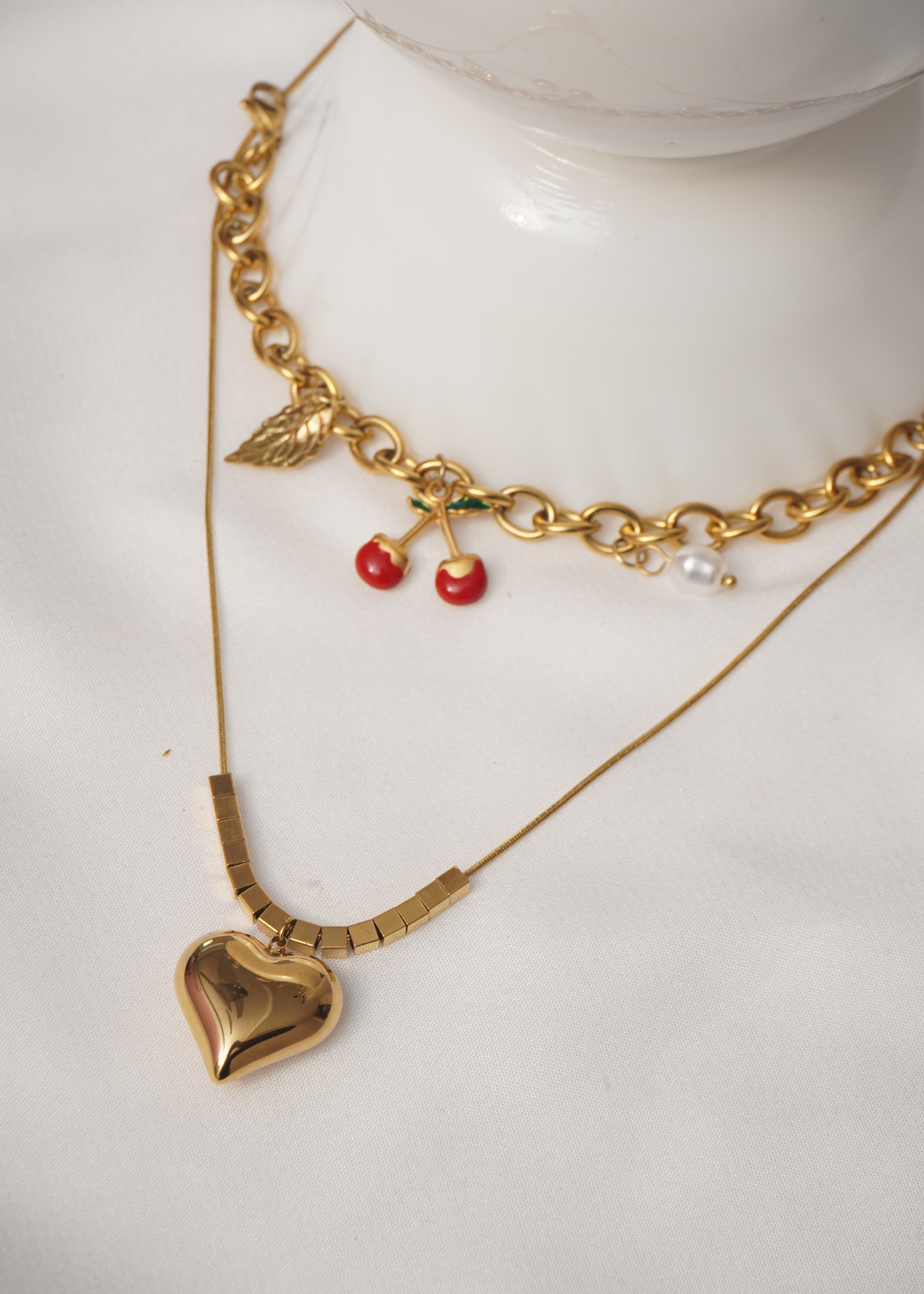 Gold bracelet with red berries and pearls on a white surface