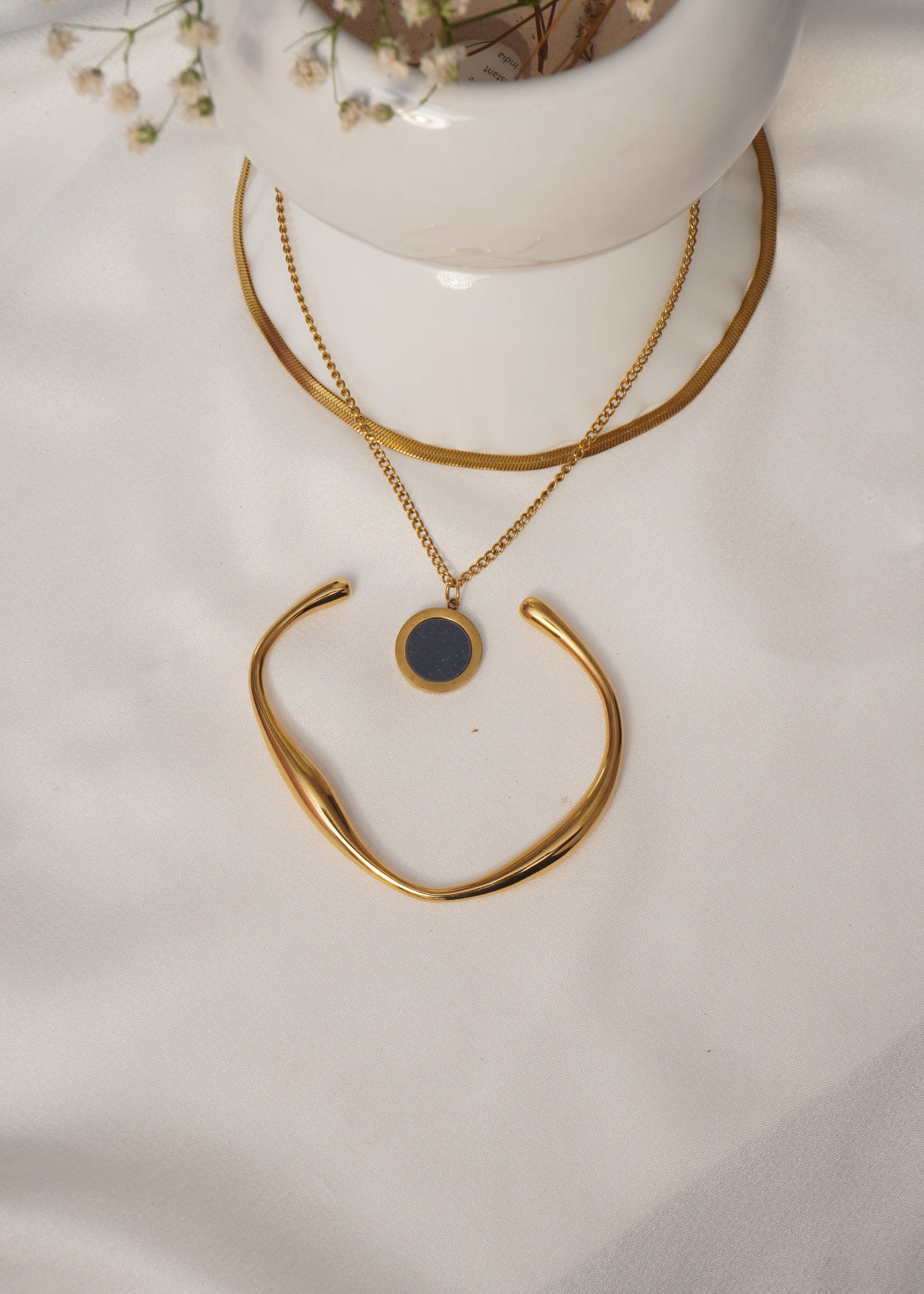 Gold necklace with a black pendant on a white surface