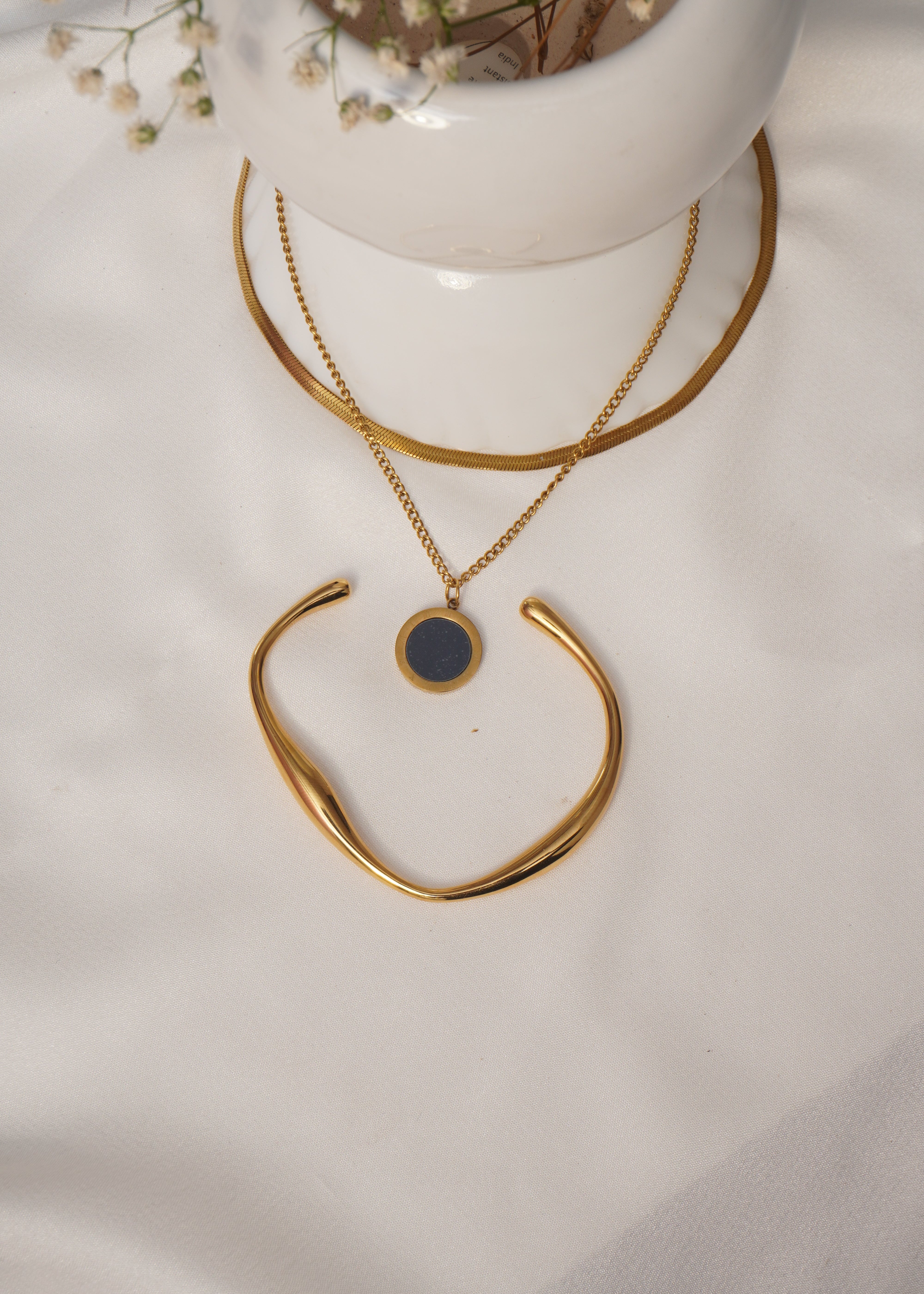 Gold necklace with a black pendant on a white surface
