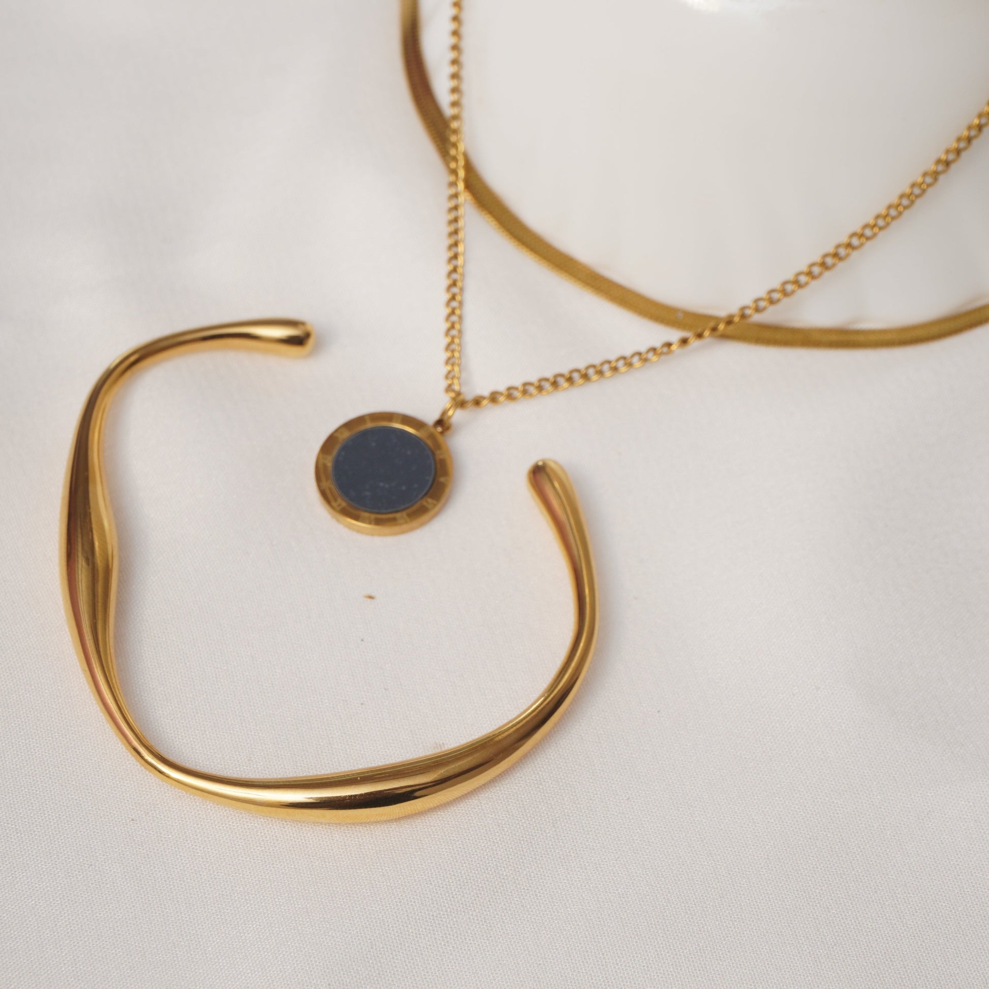 Gold bracelet and necklace on a white surface
