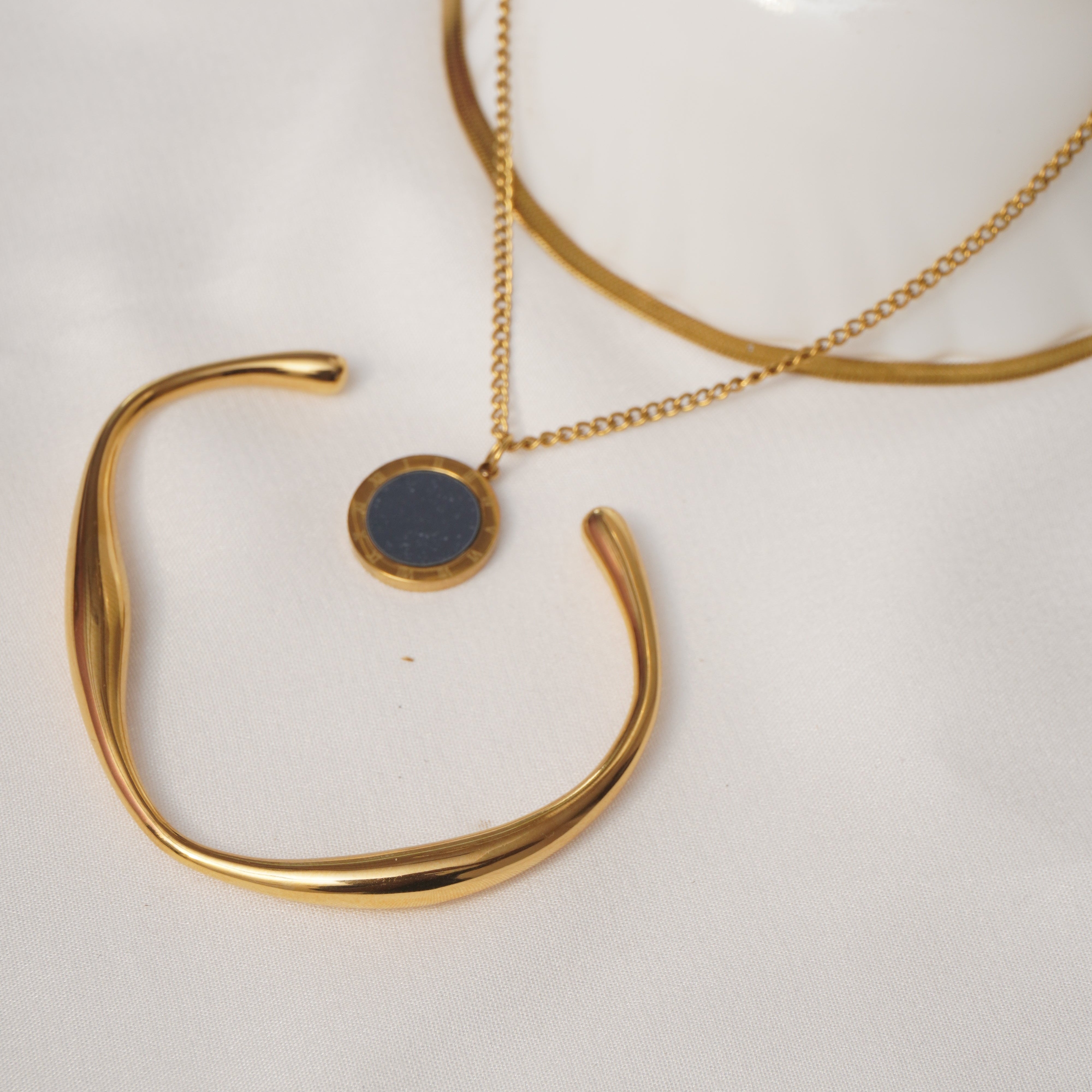 Gold bracelet and necklace on a white surface